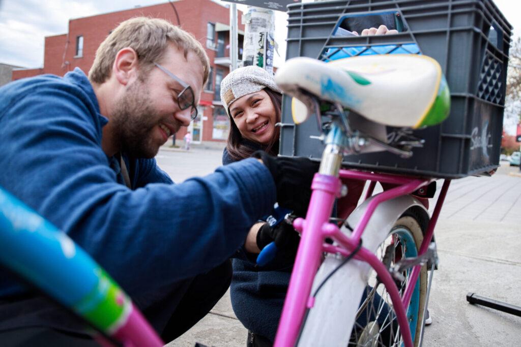 deux personnes sourient et travaillent sur un vélo coloré